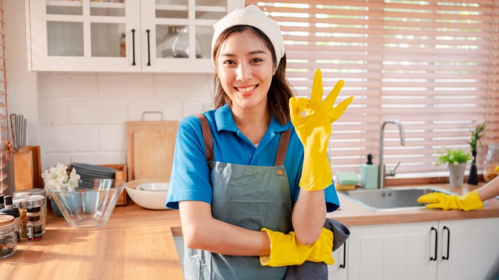 Professional maid service cleaner smiling in a spotless kitchen during a residential deep cleaning session.